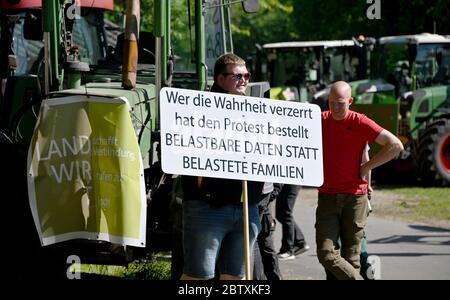 28 mai 2020, Schleswig-Holstein, Neumünster: Les agriculteurs protestataires se tiennent avec des tracteurs et une bannière disant «Whhoever a déformé la vérité a ordonné la protestation. Des données fiables au lieu des familles surchargées devant le bureau régional de l'association pour la conservation de la nature NABU. Les agriculteurs de l'initiative « Wir bitten zu Tisch » (nous leur demandons de déposer) étaient venus avec leurs tracteurs au bureau pour faire preuve de conformité aux réglementations environnementales dans le cadre d'une campagne nationale. Photo: Carsten Rehder/dpa Banque D'Images