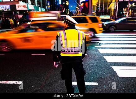 Un policier avec NYPD Vest surveille la circulation des taxis dans Times Square, Manhattan, New York City, USA Banque D'Images