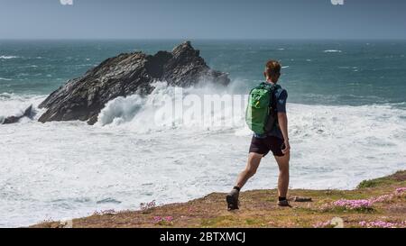 Une vue panoramique de marcheur regardant les vagues sauvages s'écraser sur Goose Island alors qu'il marche le long de la côte de Pentire point East à Newquay, dans les Cornouailles. Banque D'Images