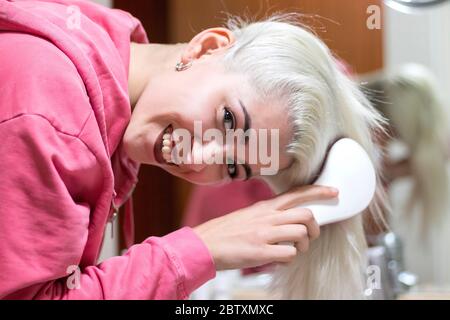 Bonne femme se brossant les cheveux avec Comb dans la salle de bains Banque D'Images