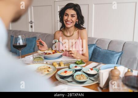 Jeune femme gaie dînant avec un monsieur au restaurant Banque D'Images