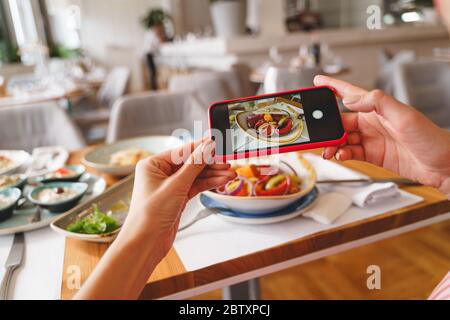 Jeune femme prenant une photo de la nourriture du déjeuner avec un téléphone portable Banque D'Images