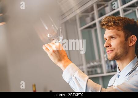 Beau jeune homme tenant un verre à vin parfaitement propre Banque D'Images