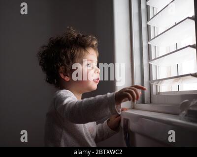 Un enfant de deux ans regarde par la fenêtre Banque D'Images