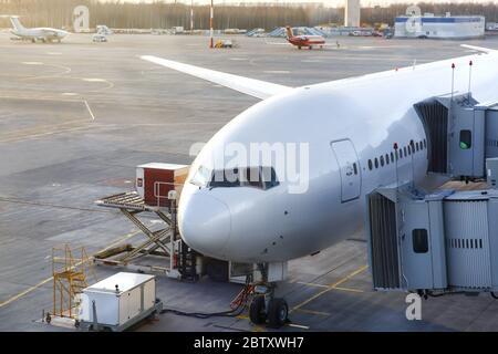 Préparation de l'avion avant le vol, connecté à une alimentation externe, prêt pour le chargement des passagers par la passerelle d'embarquement. Vue de l'airp Banque D'Images