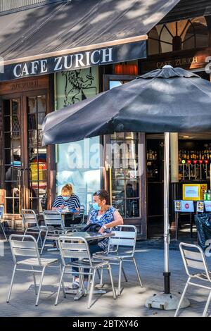 Clients avec masque chirurgical assis à table devant un café à Barcelone, Catalogne, Espagne Banque D'Images