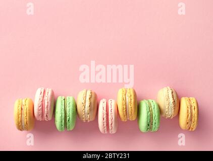 Rangée de macarons français colorés sur fond rose. Vue de dessus. Couleurs pastel Banque D'Images