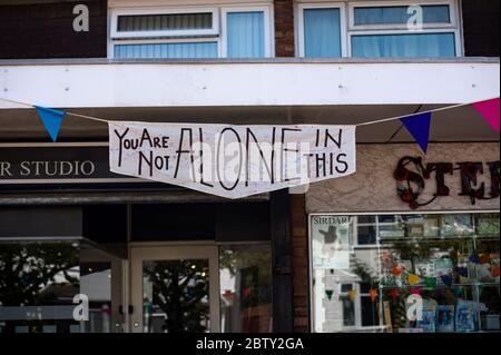 Wollaston High Street, où l'artiste Luke Perry a accroché des banderoles, avec des messages de soutien aux voisins et aux travailleurs clés, pour créer un couloir de couleur de 500 mètres à travers le village des West Midlands. M. Perry a demandé aux résidents et aux commerçants locaux de soumettre des dessins et des messages qu'il a ensuite peints et cousus à la main sur des banderoles avec l'aide de bénévoles. Banque D'Images