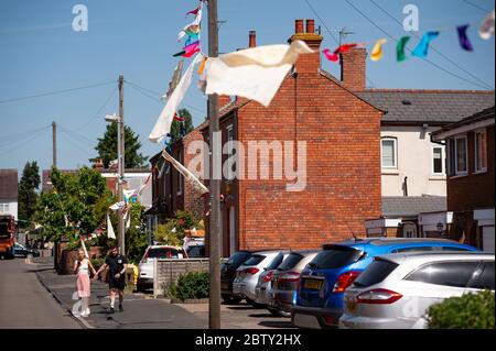 La rue Duncombe à Wollaston, où l'artiste Luke Perry a accroché des messages de soutien aux voisins et aux travailleurs clés, pour créer un couloir de couleur de 500 mètres à travers le village des West Midlands. M. Perry a demandé aux résidents et aux commerçants locaux de soumettre des dessins et des messages qu'il a ensuite peints et cousus à la main sur des banderoles avec l'aide de bénévoles. Banque D'Images