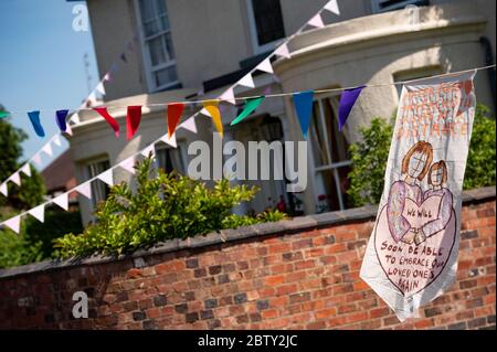 La rue Duncombe à Wollaston, où l'artiste Luke Perry a accroché des messages de soutien aux voisins et aux travailleurs clés, pour créer un couloir de couleur de 500 mètres à travers le village des West Midlands. M. Perry a demandé aux résidents et aux commerçants locaux de soumettre des dessins et des messages qu'il a ensuite peints et cousus à la main sur des banderoles avec l'aide de bénévoles. Banque D'Images