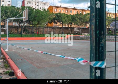 Terrain de basket-ball fermé au parc. Bandes de restriction de la police locale autour du champ vide en raison de la pandémie du coronavirus COVID-19. Banque D'Images