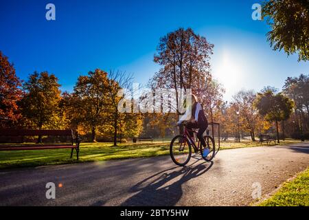 Le vélo urbain - woman riding bike in city park Banque D'Images