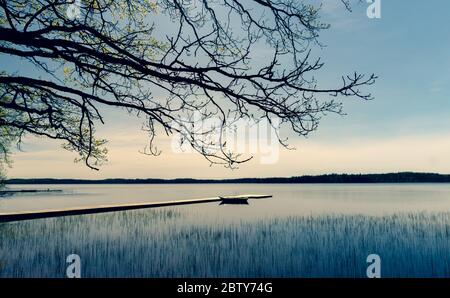 Bateau en bois amarré à un quai sur un lac au printemps Banque D'Images