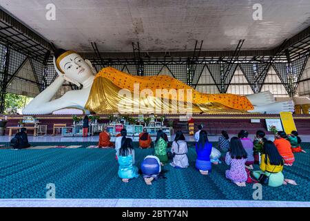 Pèlerins priant devant un Bouddha couché, pagode su Taung Pyi, Myitkyina, état de Kachin, Myanmar (Birmanie), Asie Banque D'Images