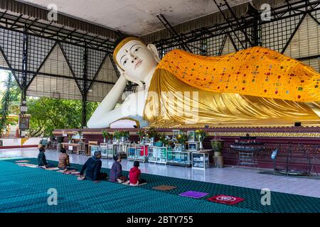 Pèlerins priant devant un Bouddha couché, pagode su Taung Pyi, Myitkyina, état de Kachin, Myanmar (Birmanie), Asie Banque D'Images