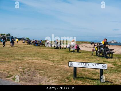 North Berwick, East Lothian, Écosse, Royaume-Uni, 28 mai 2020. Assouplissement des restrictions de verrouillage : le gouvernement écossais étant sur le point d'annoncer la levée de certaines restrictions de verrouillage aujourd'hui, des signes indiquent déjà que les choses commencent à revenir à la normale dans la populaire station balnéaire. Les bancs le long de West Bay sont entièrement occupés sous le soleil chaud, ayant été désertés au cours des dernières semaines Banque D'Images