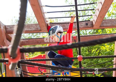 Garçon enfant enfant grimpant sur un cadre en filet à l'aire de jeux, Sopron, Hongrie Banque D'Images