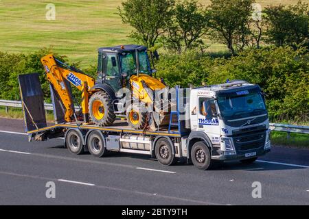 Thomas Plant Rent Wales ; livraison de camions, camion, transport, camion, remorque transportant une chargeuse-pelleteuse JCB 3CX, transporteur de chargement à bas chargement, véhicule Volvo, industrie européenne du transport commercial HGV, M6 à Manchester, Royaume-Uni Banque D'Images
