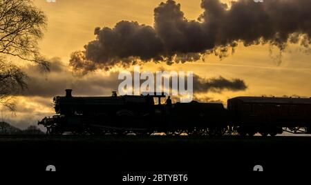 Vue latérale de l'ancienne silhouette du train à vapeur britannique, bourre dans la campagne du Worcestershire dans un magnifique coucher de soleil d'hiver. Banque D'Images