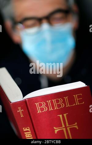 Homme lisant la bible avec un masque jetable pour éviter le coronavirus contagieux (COVID-19), France, Europe Banque D'Images