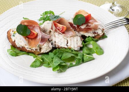 Crostini à la ricotta fumée, tomates séchées au soleil, crosse de prosciutto et glaçure balsamique. Canapés italiens traditionnels, bruschetta à la crème c Banque D'Images