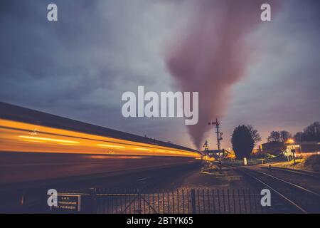 Vue rétro en soirée du train à vapeur d'époque en mouvement créant un flou de mouvement spectaculaire et rapide en quittant la gare de Kidderminster, chemin de fer du patrimoine de Severn Valley, Royaume-Uni. Banque D'Images