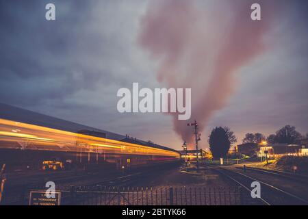 Vue rétro en soirée du train à vapeur d'époque en mouvement créant un flou de mouvement spectaculaire et rapide en quittant la gare de Kidderminster, chemin de fer du patrimoine de Severn Valley, Royaume-Uni. Banque D'Images