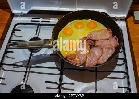 Petit déjeuner anglais, une poêle à gaz avec bacon et œufs friture Banque D'Images