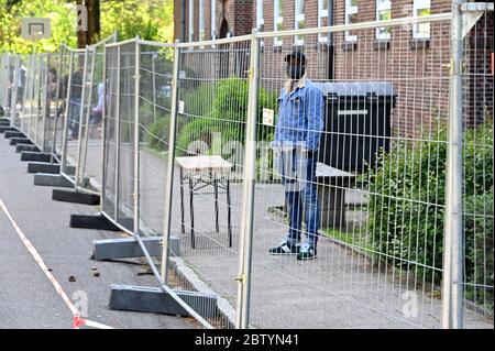 28 mai 2020, Schleswig-Holstein, Neumünster: Derrière une clôture comme mesure de protection contre l'infection, les réfugiés sont debout dans les locaux de l'Office d'Etat pour les affaires étrangères. Au cours d'une visite, le premier ministre Guenther a annoncé le nouveau nom de l'autorité. À l'avenir, il sera appelé « Bureau de l'immigration et des réfugiés. Photo: Carsten Rehder/dpa Banque D'Images