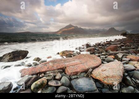 Les vagues se écrasont contre des rochers et des galets sur la baie d'Elgol, sur fond de toile de fond des Cullins noirs. Highlands, île de Skye, Écosse Banque D'Images