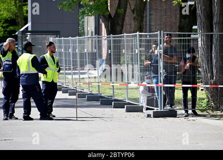 28 mai 2020, Schleswig-Holstein, Neumünster: Derrière une clôture comme mesure de protection contre l'infection, les réfugiés sont debout dans les locaux de l'Office d'Etat pour les affaires étrangères. Au cours d'une visite, le premier ministre Guenther a annoncé le nouveau nom de l'autorité. À l'avenir, il sera appelé « Bureau de l'immigration et des réfugiés. Photo: Carsten Rehder/dpa Banque D'Images