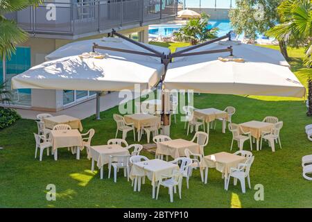 Tables en plastique blanc sous parasol dans le jardin Banque D'Images