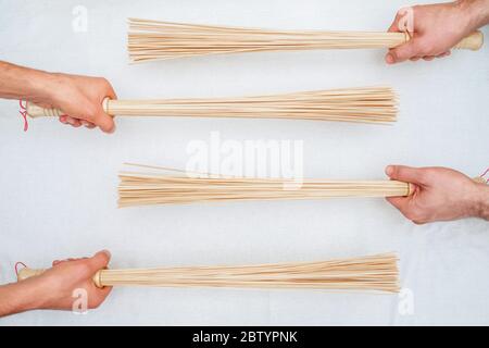 Vue de dessus des balais en bambou entre les mains de deux masseurs sur fond blanc. Banque D'Images