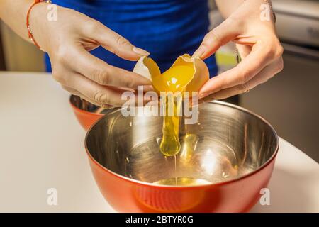 Les mains de la femme séparant le jaune d'œuf des blancs Banque D'Images