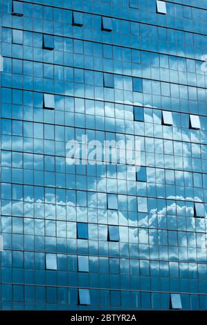 Ciel bleu et nuages réflexion ou réflexions sur la façade moderne de bâtiment en verre bleu de bureau comme concept architectural symétrique Banque D'Images