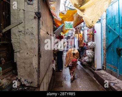 Varanasi, Uttar Pradesh, Inde - février 2015 : une femme qui marche dans une ruelle étroite bordée de boutiques dans la vieille ville. Banque D'Images