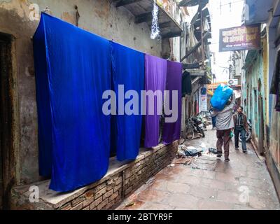 Varanasi, Uttar Pradesh, Inde - février 2015 : vêtements teints de velours et de bleu suspendus à l'extérieur d'une vieille maison dans une ruelle pavée étroite de la vieille ville. Banque D'Images