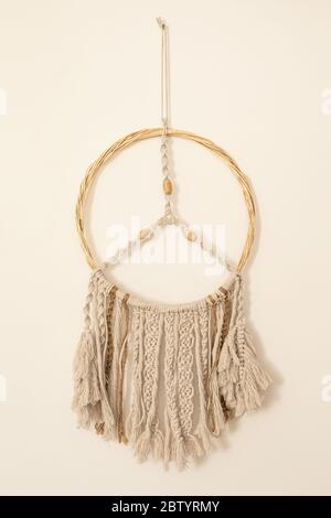 Maison bricolage décoration coton macrame pendentif mural suspendu sur un mur beige. Décoration intérieure confortable et romantique de style boho. Composition verticale Banque D'Images