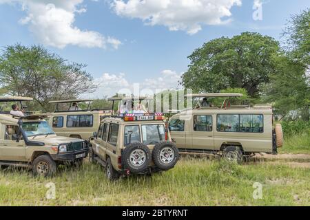 SERENGETI, TANZANIE - 15 février 2020 : les gens prennent des photos et regardent un safari en jeep au parc national de Serengeti. Jeep hors route en Afrique Banque D'Images