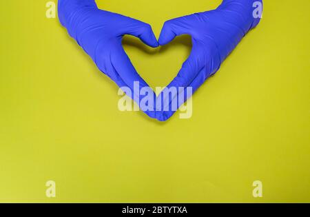 Mains avec des gants stériles en latex faisant un coeur isolé, contre COVID19 Banque D'Images