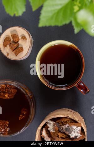 Boisson curative de chaga aux champignons de bouleau dans une tasse en céramique, pièces de champignons sur fond noir. Thé ou café de chaga. Boisson saine et tendance, super-alimentaire im Banque D'Images