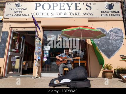 Portobello, Écosse, Royaume-Uni. 28 mai 2020. Le temps ensoleillé et chaud avec des températures atteignant 24°C a amené de nombreuses personnes à la plage et à la promenade de Portobello, Édimbourg. Le public semble avoir le sentiment que le verrouillage est détendu sont profiter du bon temps pour bronzer et profiter des nombreux cafés qui offrent maintenant des collations à emporter. Photo. Busker à l'extérieur du café ouvert sur Portobello High Street. Iain Masterton/Alay Live News Banque D'Images