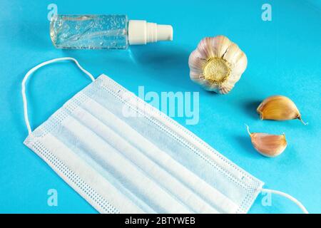 Masque médical, ail et gel alcool sur fond bleu. Concept de protection contre le coronavirus et le virus de la grippe. Mise au point sélective Banque D'Images