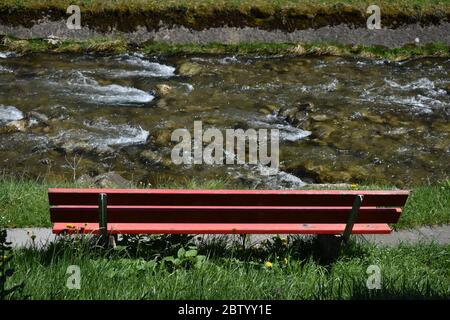 Banc rouge vide à côté d'une rivière Banque D'Images