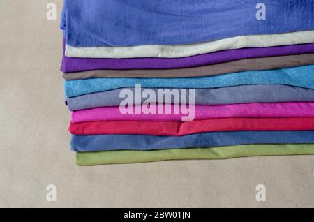 Dix t-shirts de différentes couleurs. Ensemble de t-shirts multicolores. Une pile de t-shirts tendance en gros plan. Tenue confortable et décontractée. Mise au point sélective. Banque D'Images