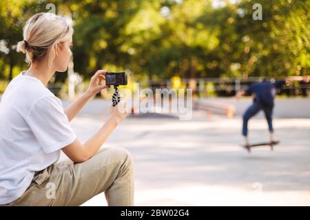 Cool fille enregistrant une nouvelle vidéo de jeune patineuse sur le skateboard pour vlog passant du temps à un skate moderne Banque D'Images