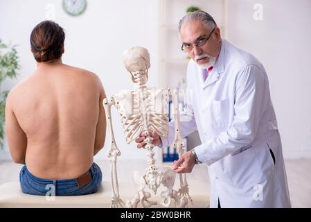 Jeune homme blessé au dos, rendant visite à un médecin expérimenté Banque D'Images