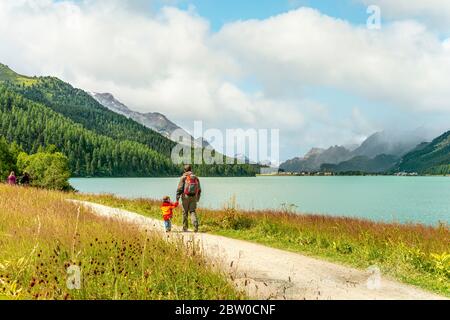 Père et son randonnée au bord du lac Silvaplana dans un paysage de montagne Banque D'Images