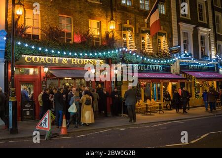 Les personnes qui apprécient un verre à l'extérieur du pub Coach and Horses à Covent Garden la nuit pendant Noël. Londres Banque D'Images