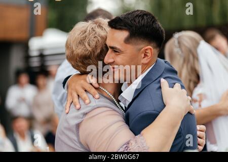 Joyeux marié emRacing sa mère pendant la cérémonie de mariage Banque D'Images